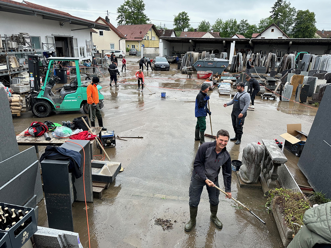 Mitarbeiter eines Steinmetz Babenhausen beseitigen Überschwemmung auf Firmengelände